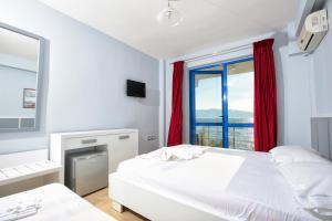 a bedroom with a white bed and a window at Hotel Nimfa in Vlorë