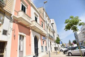 ulica z różowym budynkiem i zaparkowanymi samochodami w obiekcie Ai Raggi di Sole w mieście Lecce