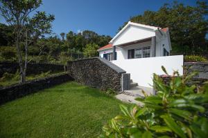 a white house with a stone wall and a yard at Casa do Chafariz (Casas do Capelo) in Varadouro