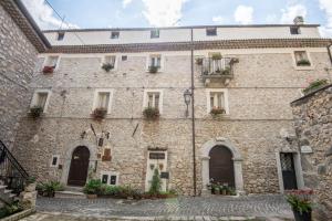 a large stone building with flowers on the windows at Nenà Al Borgo Castello in Pico