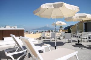 a patio with white chairs and tables and umbrellas at Hotel Crawford in Sant'Agnello