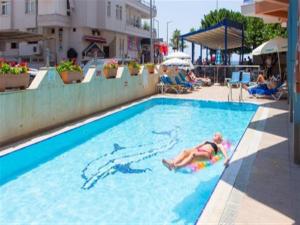 a woman laying on a raft in a swimming pool at Kleopatra Balik Hotel in Alanya +36 photos