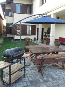a picnic table with a grill and an umbrella at Apartmani Radulović in Vrnjačka Banja