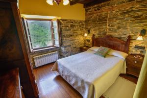 1 dormitorio con cama y pared de ladrillo en A Casoa, en Santa Eulalia de Oscos
