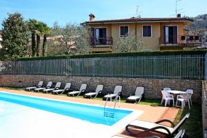 a pool with chairs and a table and a house at Casa Orchidea Apartments in Torri del Benaco