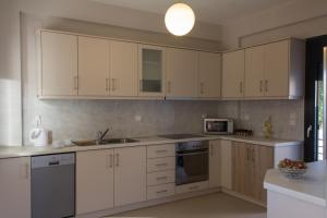 a kitchen with white cabinets and stainless steel appliances at Perivoli House A in Skala Eresou