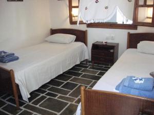 a room with two beds and a table and a mirror at Pension Irini-Vicky in Ios Chora