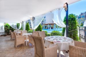 a patio area with chairs, tables and umbrellas at Aparthotel Dawn Park in Sunny Beach