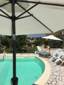 a swimming pool with an umbrella and chairs and a table at Casa Vacanze Agriturismo Cilone in Ragusa