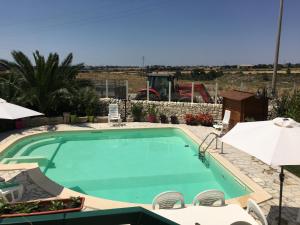 a large swimming pool with chairs and umbrellas at Casa Vacanze Agriturismo Cilone in Ragusa