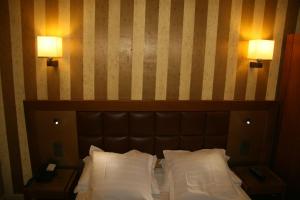 a bed with two lamps on a striped wall at Hotel Bellevue Saint-Lazare in Paris