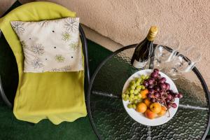 a glass table with a plate of fruit and a bottle of wine at Vági Apartment in Sárvár
