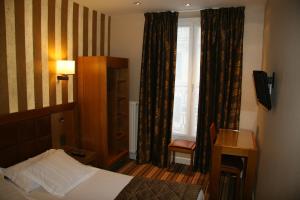a bedroom with a bed and a window with curtains at Hotel Bellevue Saint-Lazare in Paris