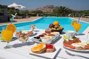 una mesa con desayuno y bebidas junto a una piscina en Moongarden Resort, en Mithimna