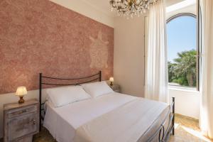 a bedroom with a bed and a window and a chandelier at Antica Villa in Gaeta +14 photos