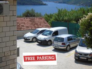 three cars parked in a parking lot with a free parking sign at Apartments Jovanović in Perast