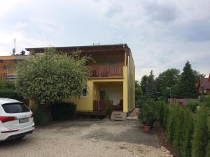 a yellow house with a car parked in front of it at Margitapartman in Bük