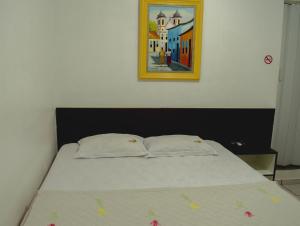 a bed with two pillows and a picture on the wall at Pousada Tambaú in São Luís +35 photos