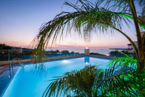 a swimming pool with a palm tree in front of a sunset at Esplanade Apartments - Heated Pool in Kalathas +154 photos