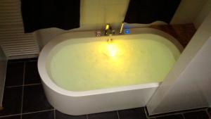 Luxe kamer Cadzand في كادزاند: حوض استحمام وشمعة فيه حمام