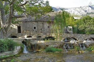 an old stone building next to a river with a bridge at Apartment Gamma with hydromassage mini pool near Split in Žrnovnica