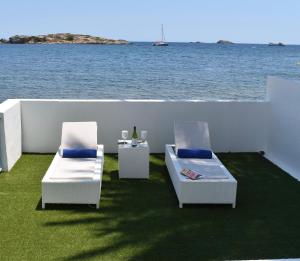 two chairs and a table with a view of the water at Enkala Apartamentos in Ibiza Town