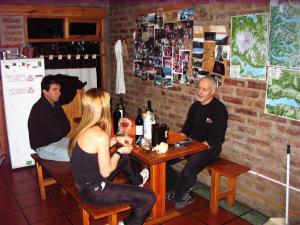 un grupo de personas sentadas en una mesa con botellas de vino en Puma Hostel en San Martín de los Andes