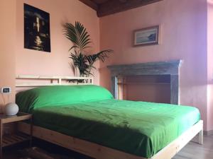 a bedroom with a green bed and a fireplace at Appartamenti Edvina in Baveno