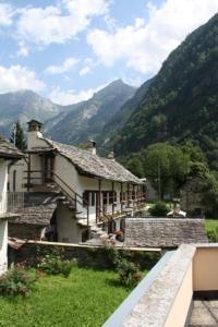 un grupo de casas con montañas en el fondo en Ristorante Alpino en Sonogno