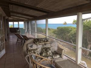 a porch with a couch and chairs and the ocean at Coconut Beach House in Green Turtle Cay