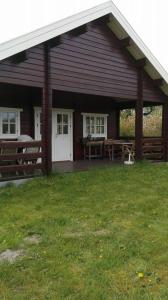 ein Haus mit einer Terrasse, einem Tisch und Bänken in der Unterkunft Hovborg Ferieby - Torpet 126 in Hovborg