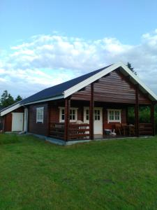 eine große Holzhütte mit einem Grasfeld davor in der Unterkunft Hovborg Ferieby - Torpet 126 in Hovborg