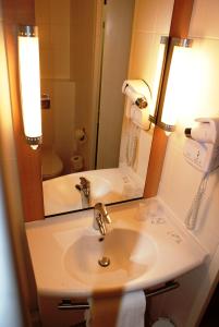 ein Bad mit einem Waschbecken und einem Spiegel in der Unterkunft ibis Hotel Brussels Expo Atomium in Brüssel