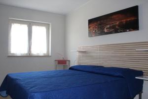 1 Schlafzimmer mit einem blauen Bett und 2 Fenstern in der Unterkunft L'occhio sul Vesuvio appartamento con terrazza privata e casa vacanza senza terrazza privata in Neapel