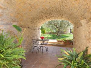 un patio con mesa y sillas bajo una pared de piedra en Can Barrull, en Sant Feliu de Boada