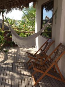 2 sillas y una hamaca en el porche en Cabana Chic, en Tatajuba