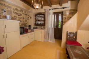 a kitchen with white cabinets and a stone wall at kritikies1 in Pitsidia