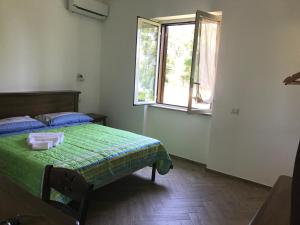 a bedroom with a green bed and a window at Luna D'Agerola in Agerola