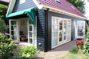 a black and white shed with a red roof at Zomerhuisje op Huisduinen in Huisduinen