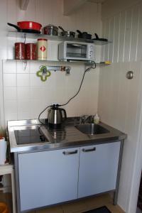 a small kitchen with a sink and a microwave at Zomerhuisje op Huisduinen in Huisduinen