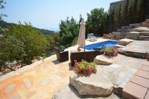 a patio with a pool and an umbrella and flowers at Lloret Apartments in Lloret de Mar