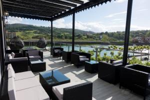 a patio with chairs and tables and a view of a river at Hotel Boutique Bahía de Plentzia in Plentzia