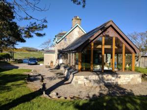 an old stone house with a conservatory at Auchencairn Cottage in Brora