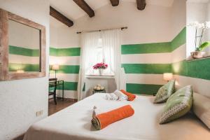 a bedroom with a white bed with green and white stripes at Borgo degli Ulivi in Porto Ercole