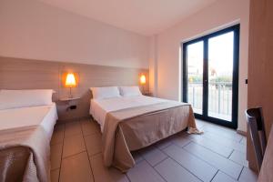 a hotel room with two beds and a window at Longomare in Corigliano Calabro