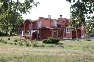 a red house with a yard in front of it at Apartments Matelici in Divšići