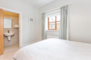 a white bedroom with a bed and a sink at Garryvoe Beach Homes in Garryvoe