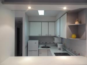 - une cuisine blanche avec des placards blancs et un évier dans l'établissement Apartamentos Blaumar, à L'Estartit