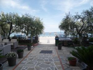 une terrasse avec des arbres et une plage en arrière-plan dans l'établissement Plage Hotel, à Néa Péramos