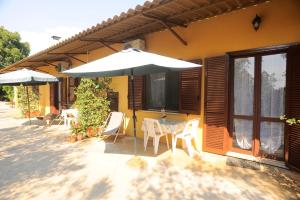 eine Terrasse mit einem Sonnenschirm, einem Tisch und Stühlen in der Unterkunft Agriturismo La Giannottola in Aprilia